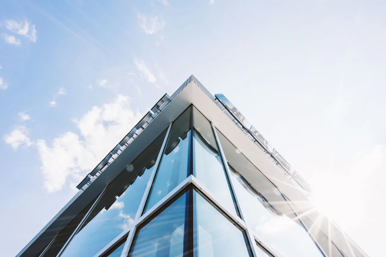 The glass corner of an office tower seen from below
